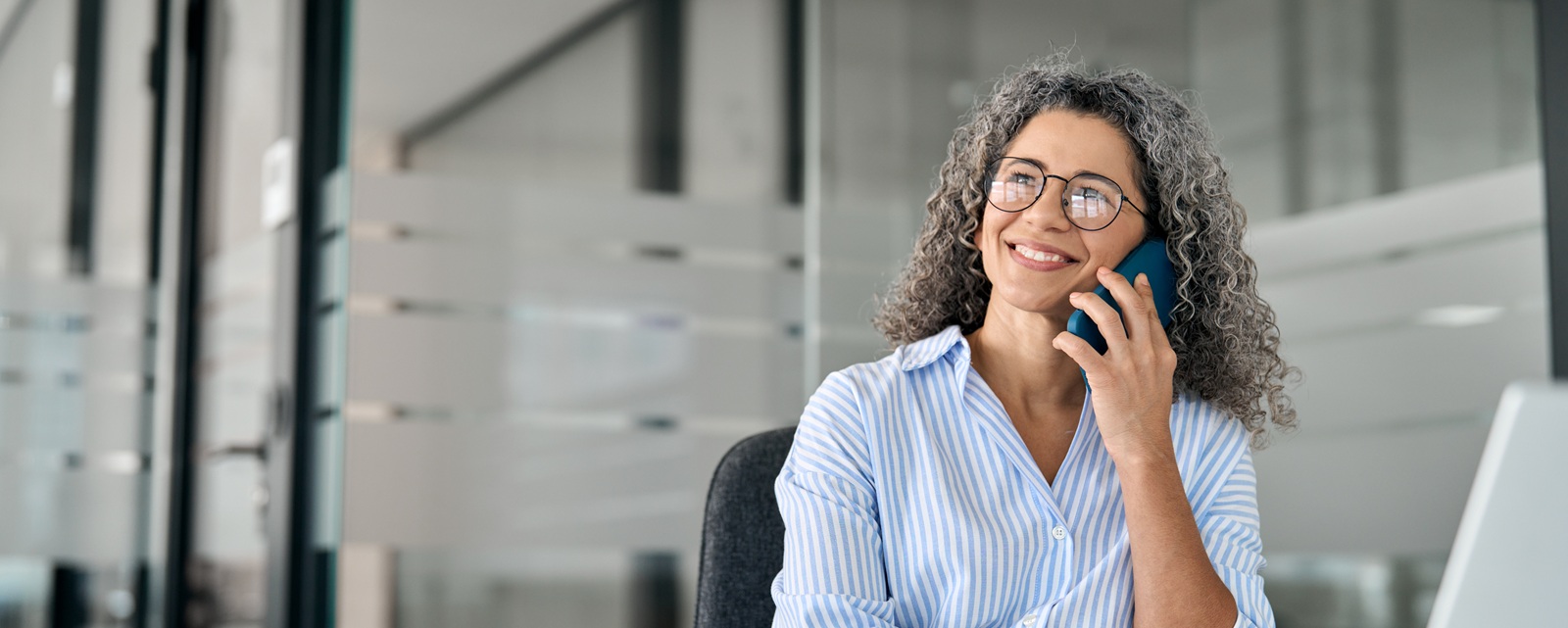 Femme souriante au téléphone à son bureau, bannière de la page contact