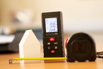 Télémètre laser et mètre ruban sur une table, mesure de la surface habitable (loi Boutin)