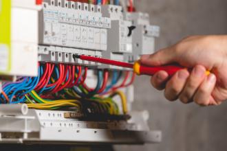 Tournevis sur un tableau électrique ouvert aux fils colorés, diagnostic électricité