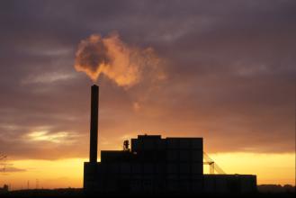Usine et cheminée fumante au coucher du soleil, illustration de l'état des risques et pollutions