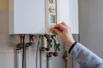 Main réglant une chaudière murale à gaz avec tuyaux cuivre, diagnostic gaz
